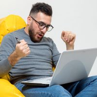 a guy rejoice while working on laptop